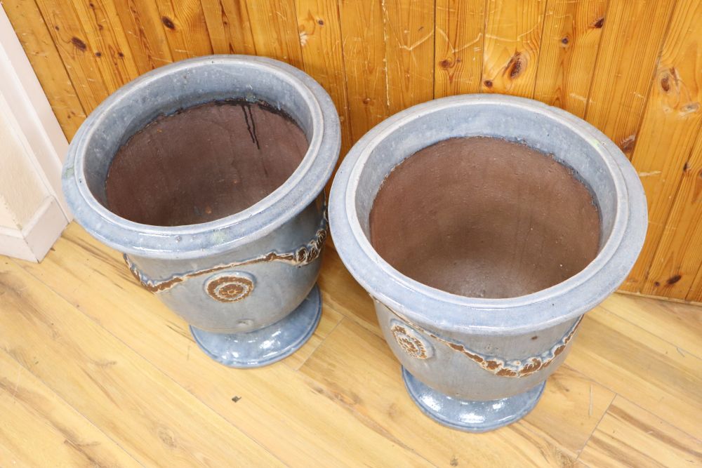 A pair of blue glazed terracotta pots, with swag design, height 51cm